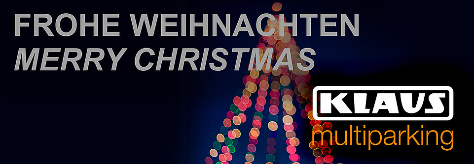 Frohe Weihnachten Merry Christmas vor einem beleuchteten Weihnachtsbaum, links unten Logo KLAUS Multiparking