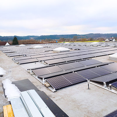 Dach mit Photovoltaik-Anlagen, im Hintergrund Landschaft und Himmel