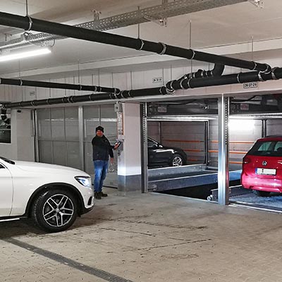 Ein Mann steuert ein Parksystem, ein Auto steht davor