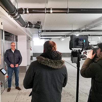 Zwei Männer machen ein Interview, ein Kameramann filmt mit